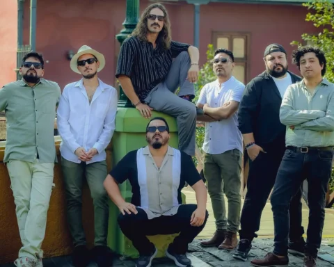 Los siete integrantes de Olaya Sound System posan junto a un farol de tres globos frente a una casona de balcones verdes