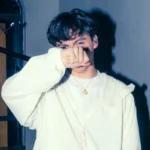 Sobresdylan con traje blanco tapándose la cara